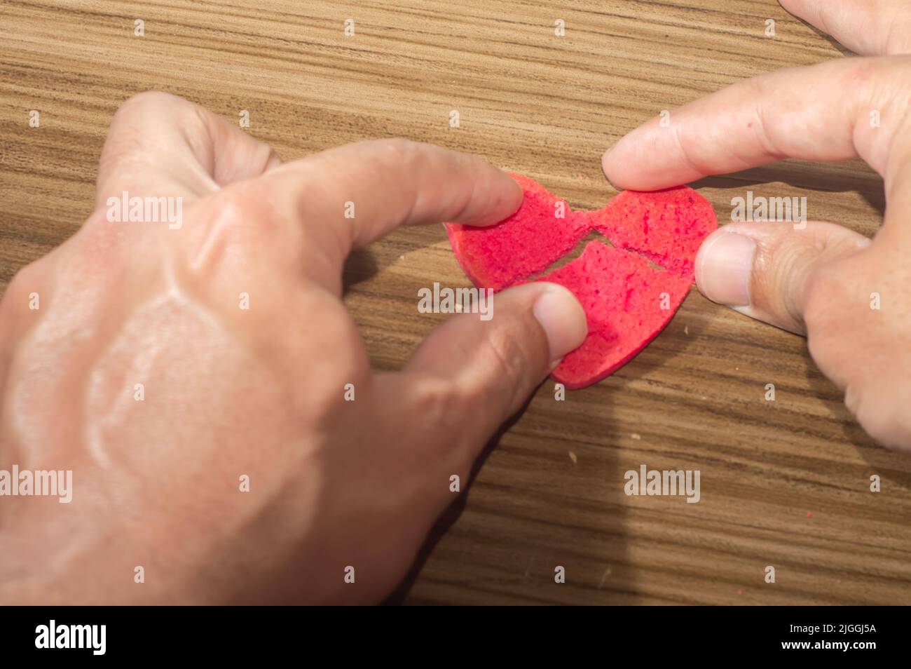 Rottura del lavoro del cuore in pezzi, rottura del biscotto a forma di cuore su un tavolo di legno. Foto Stock