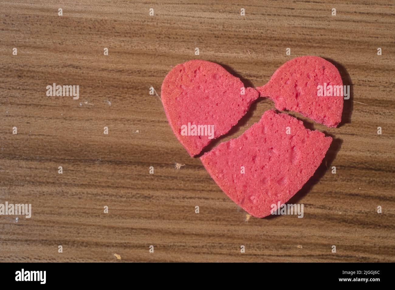 Rottura del lavoro del cuore in pezzi, rottura del biscotto a forma di cuore su un tavolo di legno. Foto Stock