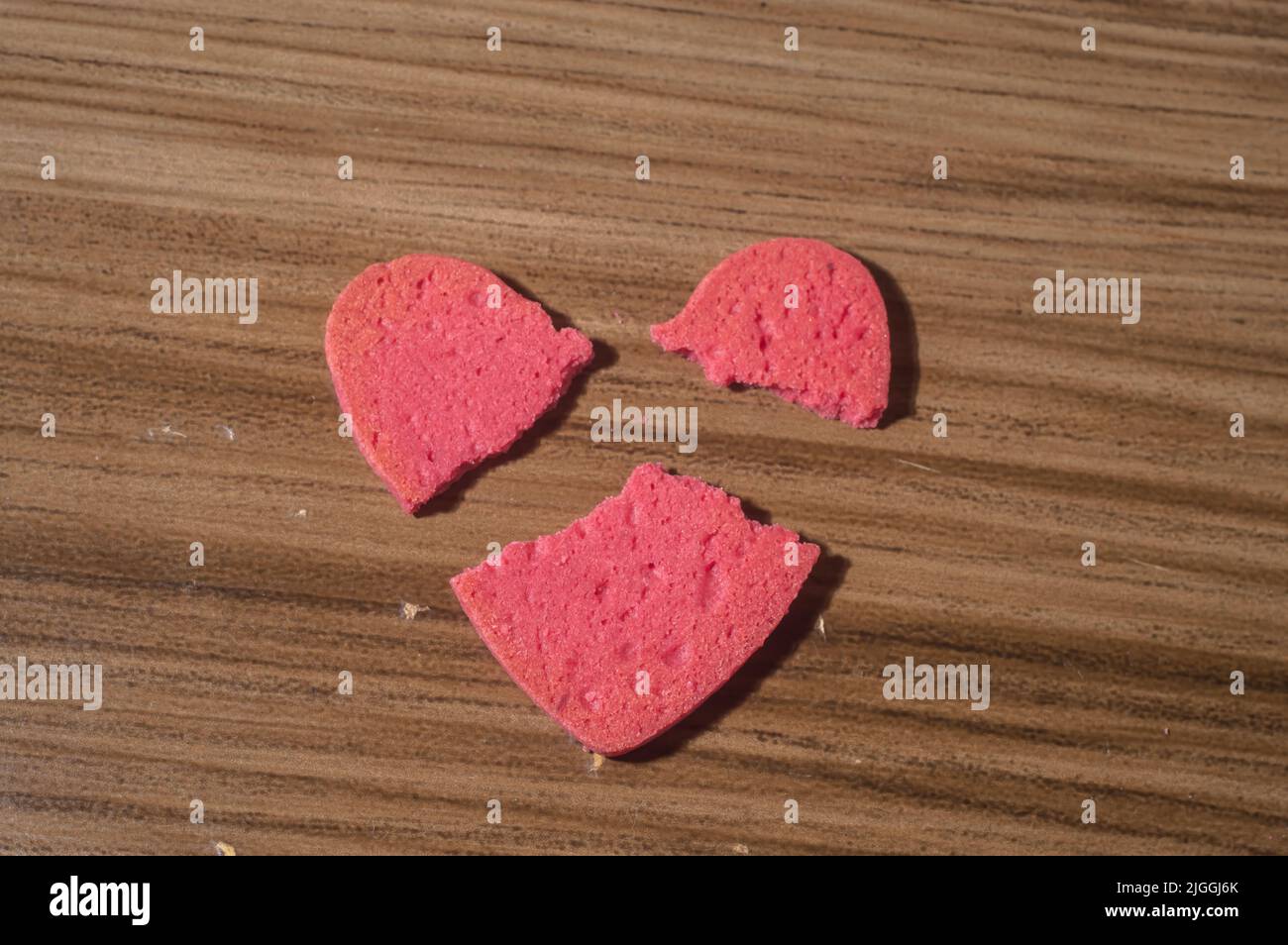 Rottura del lavoro del cuore in pezzi, rottura del biscotto a forma di cuore su un tavolo di legno. Foto Stock