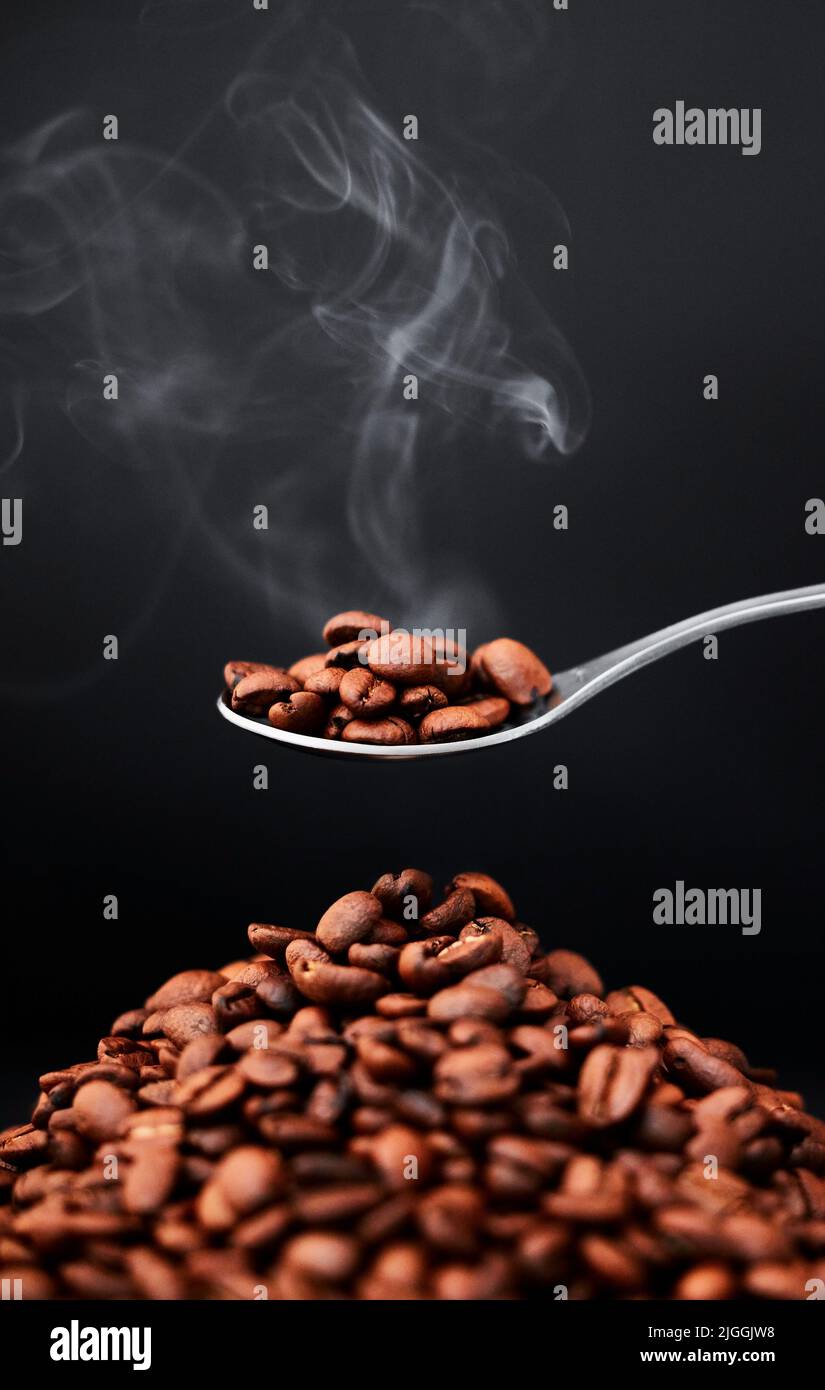 Un cucchiaino è tutto ciò che serve. Shot di chicchi di caffè ancora più realistici su sfondo grigio. Foto Stock