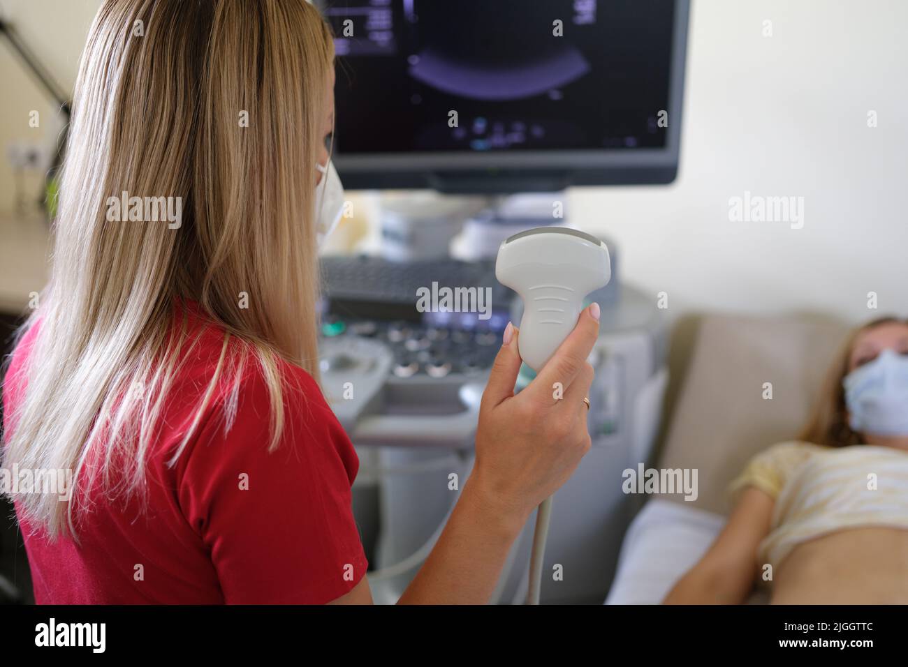 Medico donna che tiene il trasduttore a ultrasuoni ed esamina il paziente Foto Stock