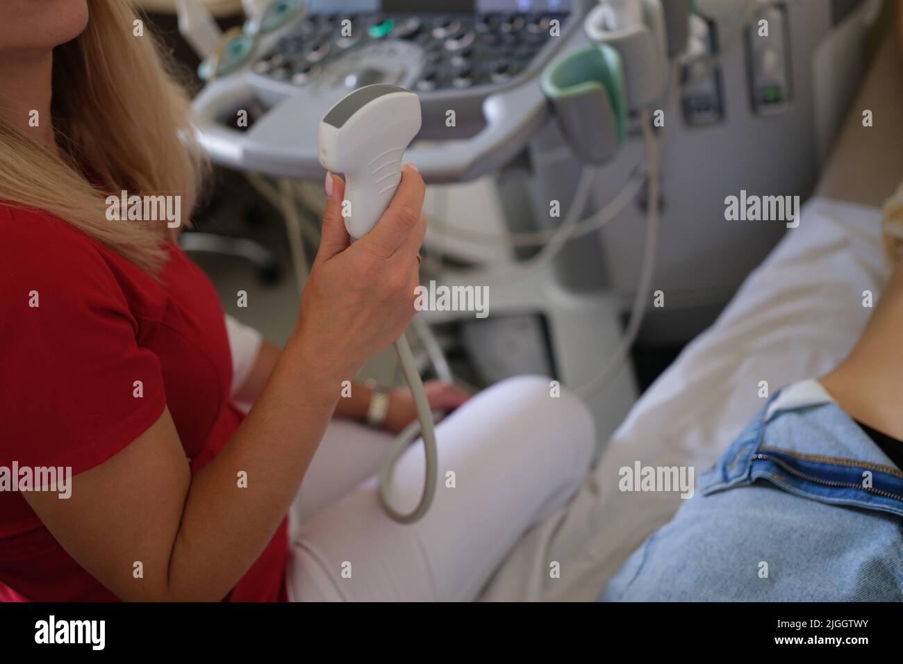 Medico che tiene il trasduttore a ultrasuoni e fa lo screening del paziente Foto Stock