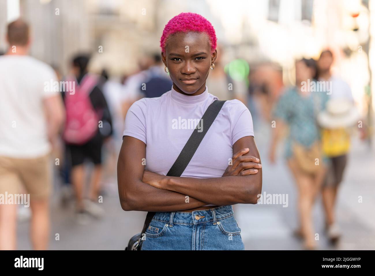 Donna afro seria che guarda la macchina fotografica con le braccia incrociate all'aperto Foto Stock