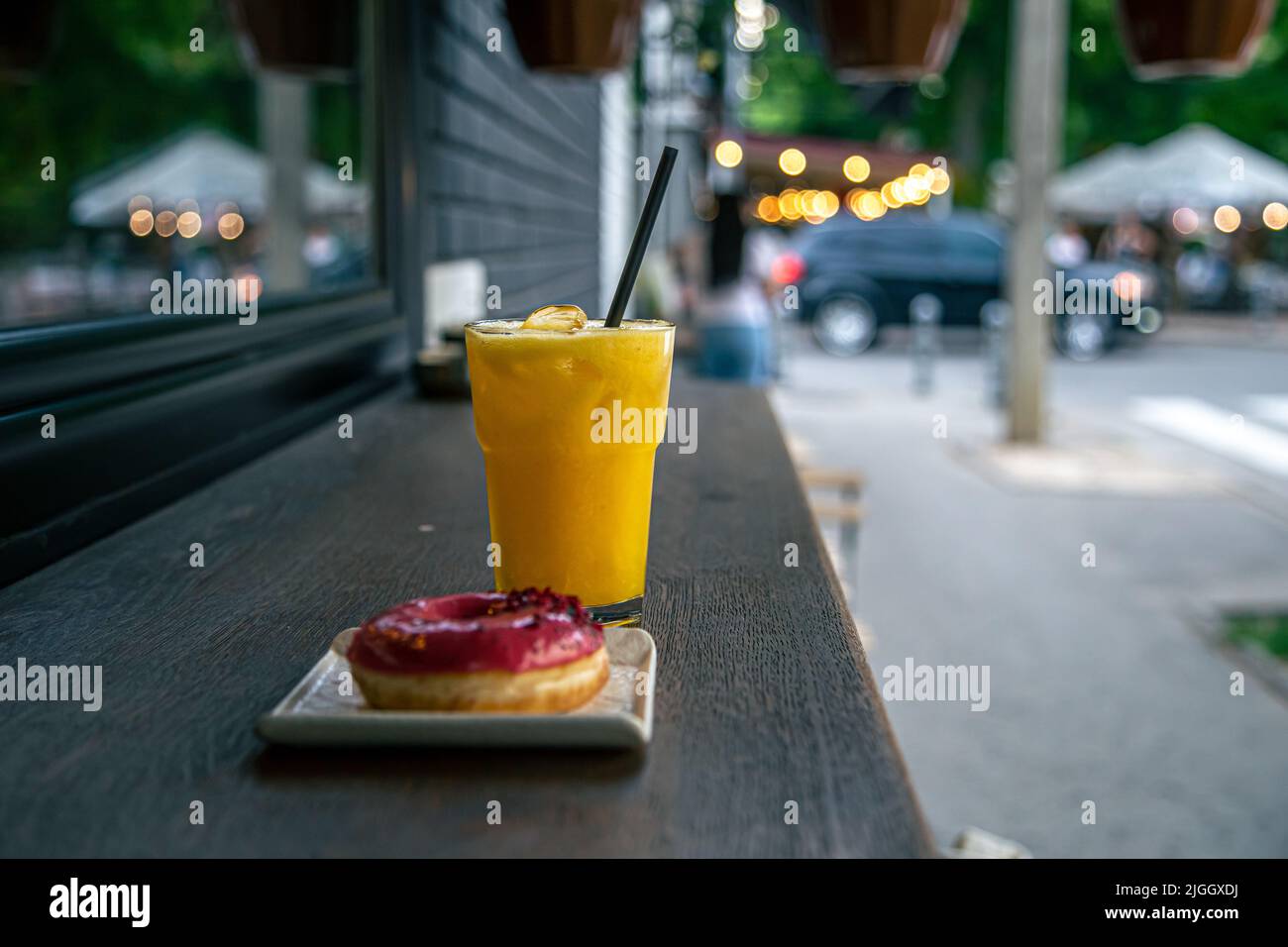 Primo piano, succo e ciambella su uno sfondo sfocato della città. Foto Stock