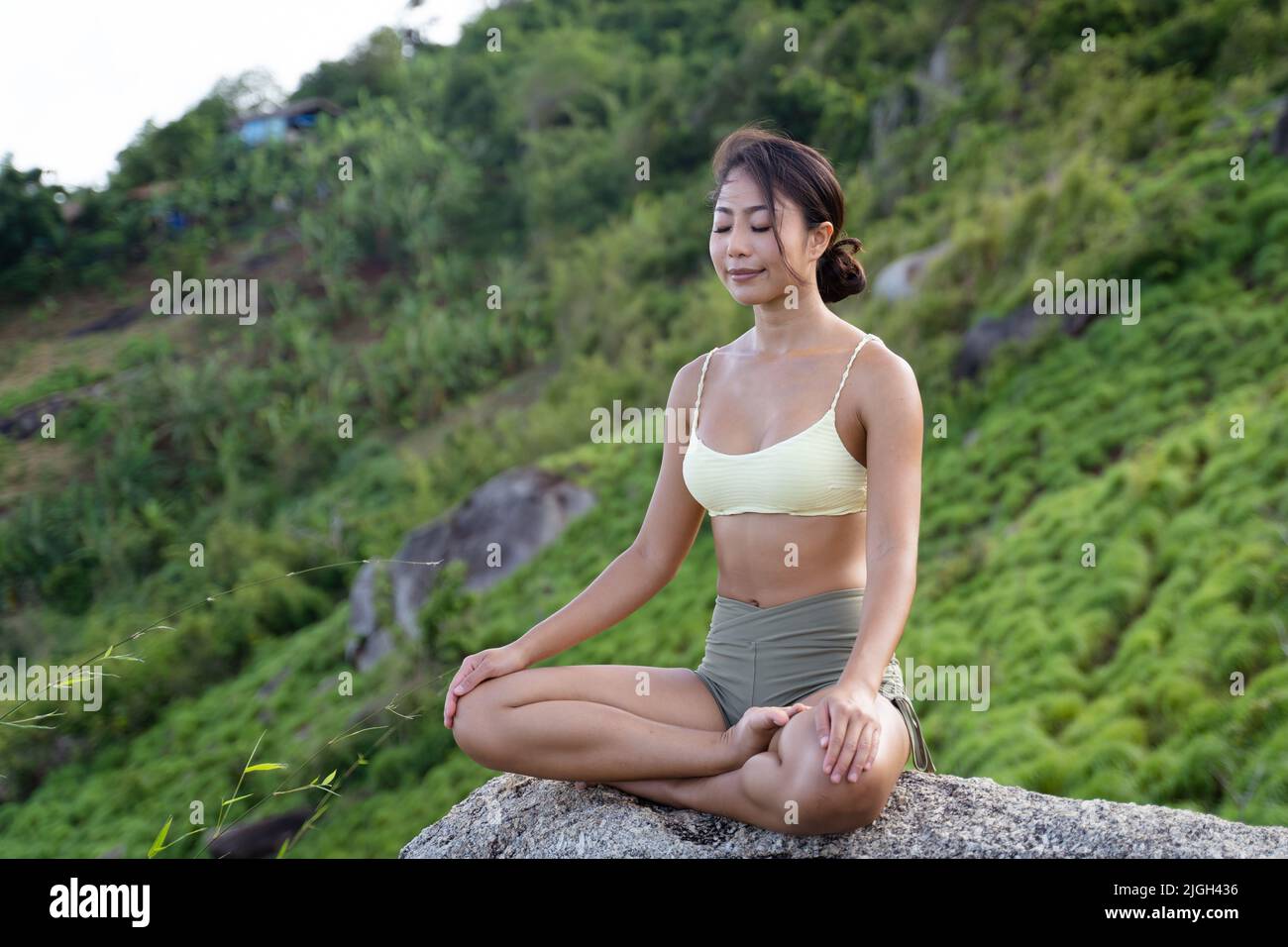 Giovane donna asiatica che fa meditazione sulla cima della collina di montagna. Momento tranquillo e tranquillo Foto Stock