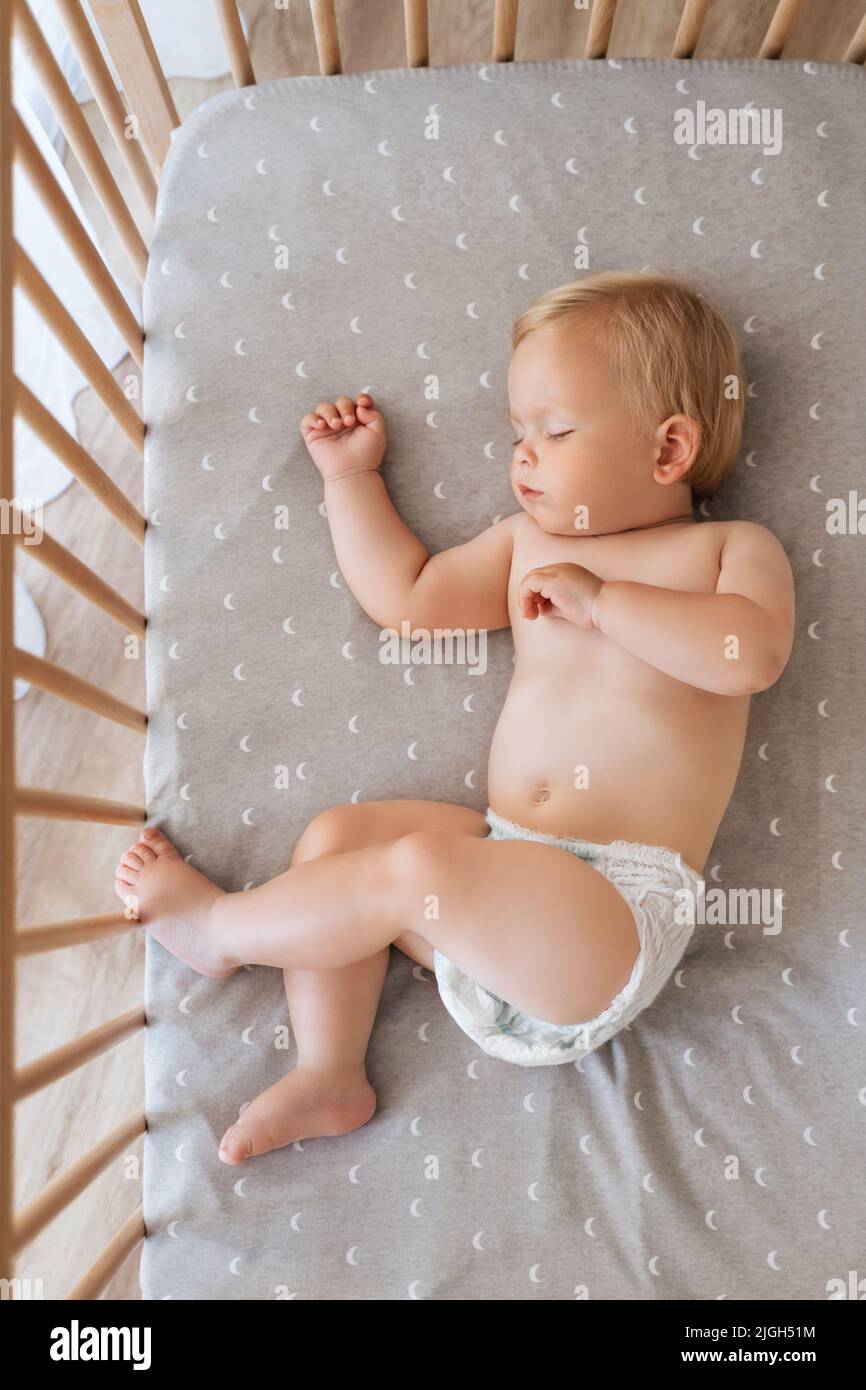 Ritratto della vista superiore del bambino piccolo ragazzo in pannolino sdraiato nel suo letto napping guardando sogni dolci. Sonno sicuro per i bambini. Concetto di assistenza all'infanzia. Buona infanzia Foto Stock