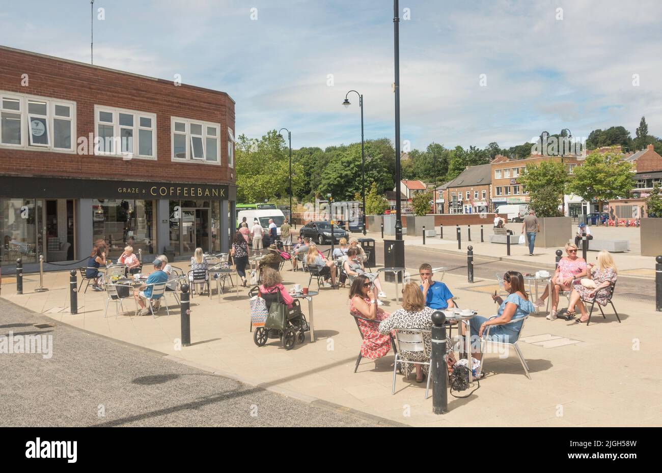 Persone che si siedono al di fuori di una caffetteria al sole estivo, Chester le Street, Co. Durham, Inghilterra, Regno Unito Foto Stock