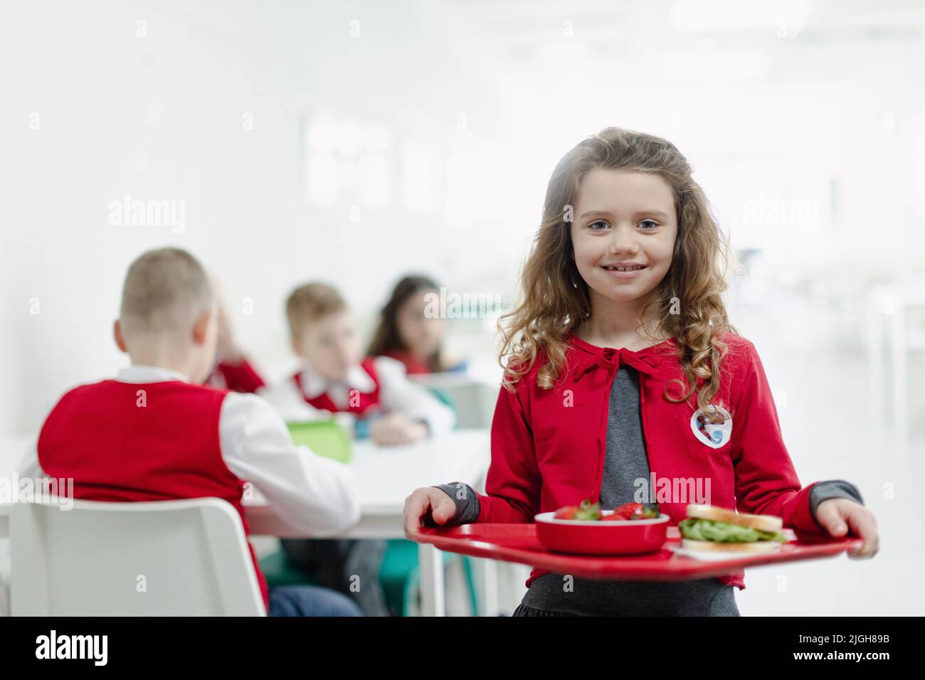 Buon grirl scolaro in uniforme vassoio con pranzo in mensa scolastica. Foto Stock