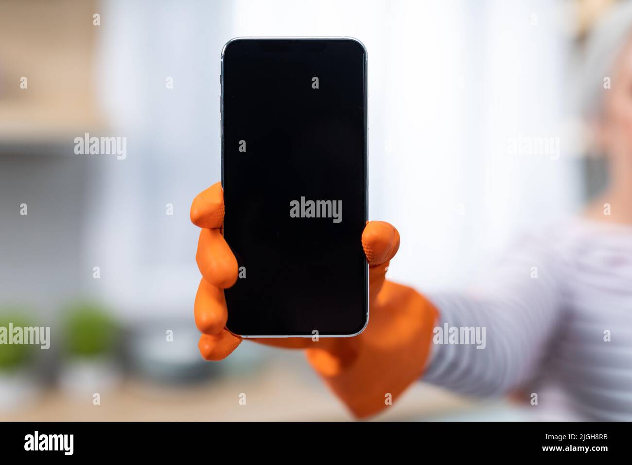 Offerta online. Irriconoscibile Lady indossa un guanto in gomma che tiene grande smartphone vuoto Foto Stock