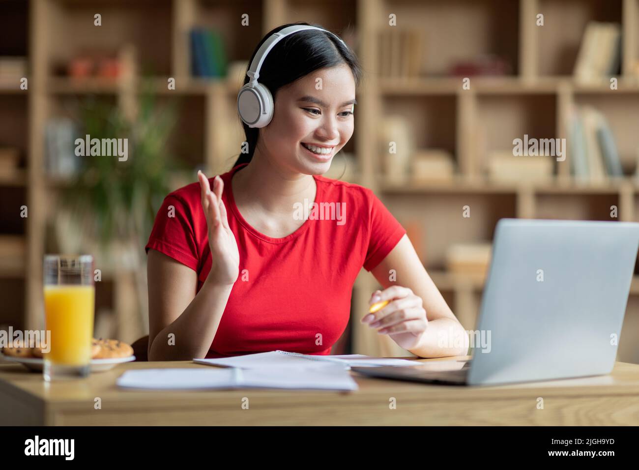 Felice adolescenza felice studente asiatico signora in cuffie hanno riunione a distanza guardando il computer Foto Stock