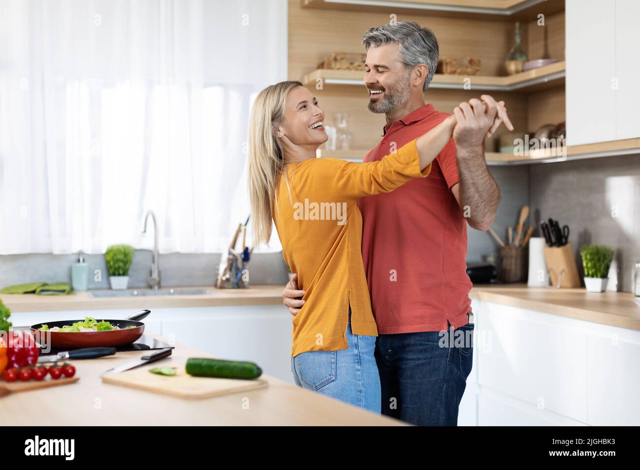 Romantica coppia di mezza età ballare mentre cucinano insieme Foto Stock