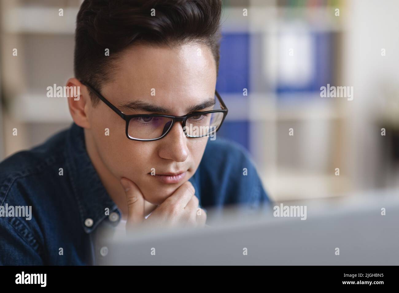 Ritratto di giovane bel ragazzo in occhiali guardando lo schermo del computer Foto Stock