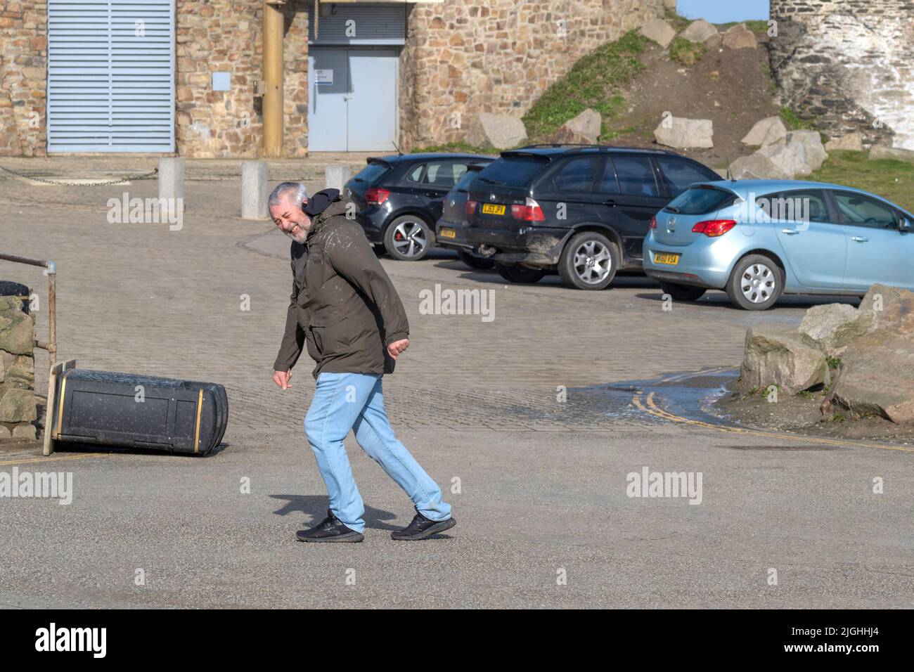 Un uomo che lotta per attraversare un parcheggio in forte vento portato nel Regno Unito da Storm Eunice. Newquay in Cornovaglia. Foto Stock