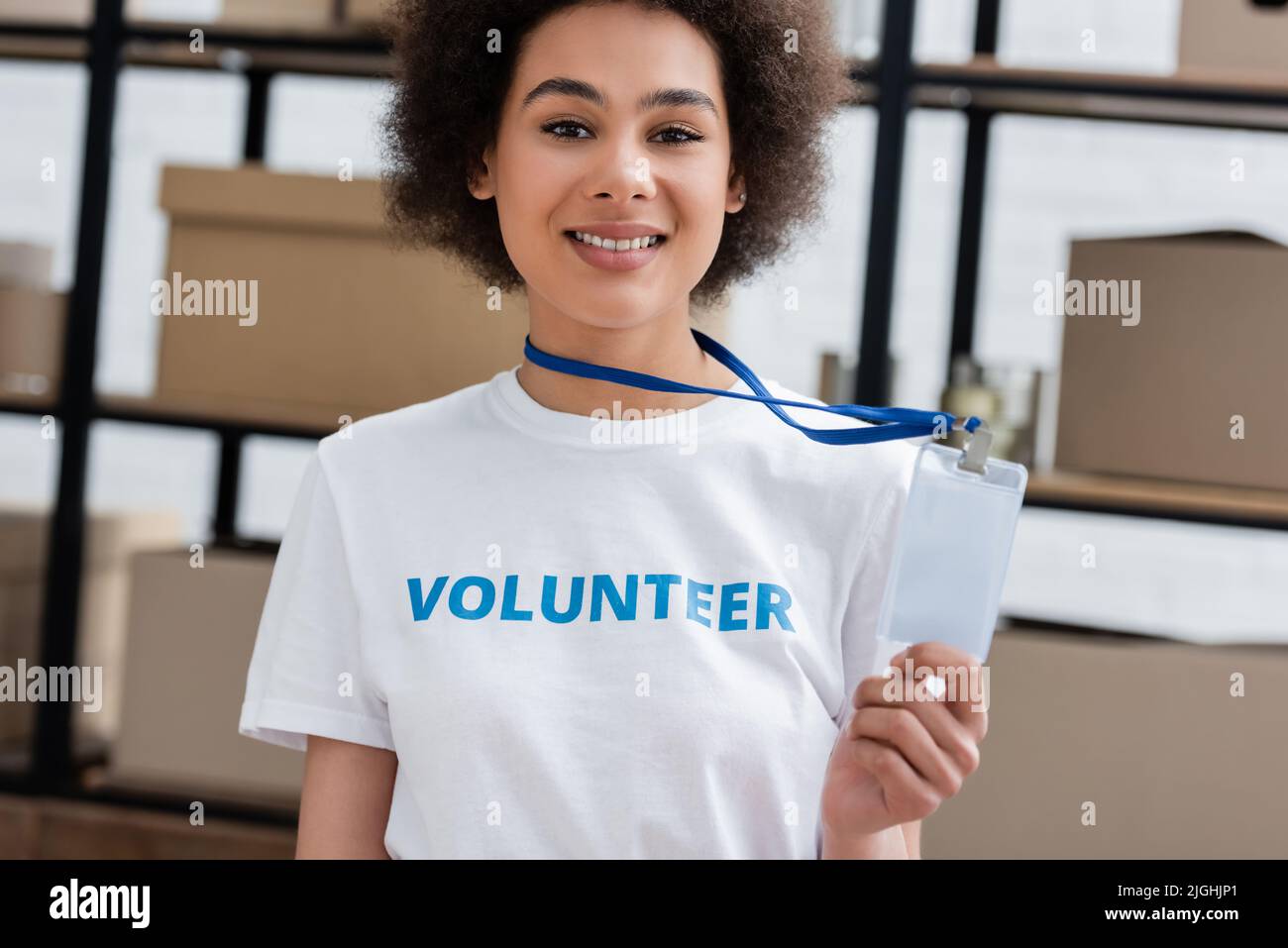 un volontario allegro afroamericano che mostra una carta d'identità vuota nel centro di donazione Foto Stock