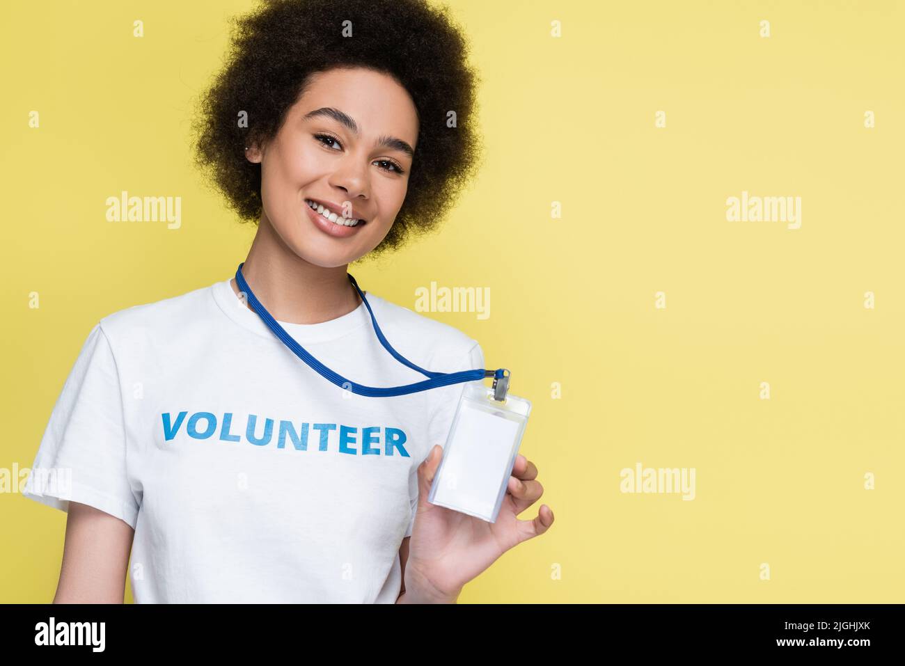 un volontario afro-americano sorride alla macchina fotografica e mostra una carta d'identità vuota isolata in giallo Foto Stock