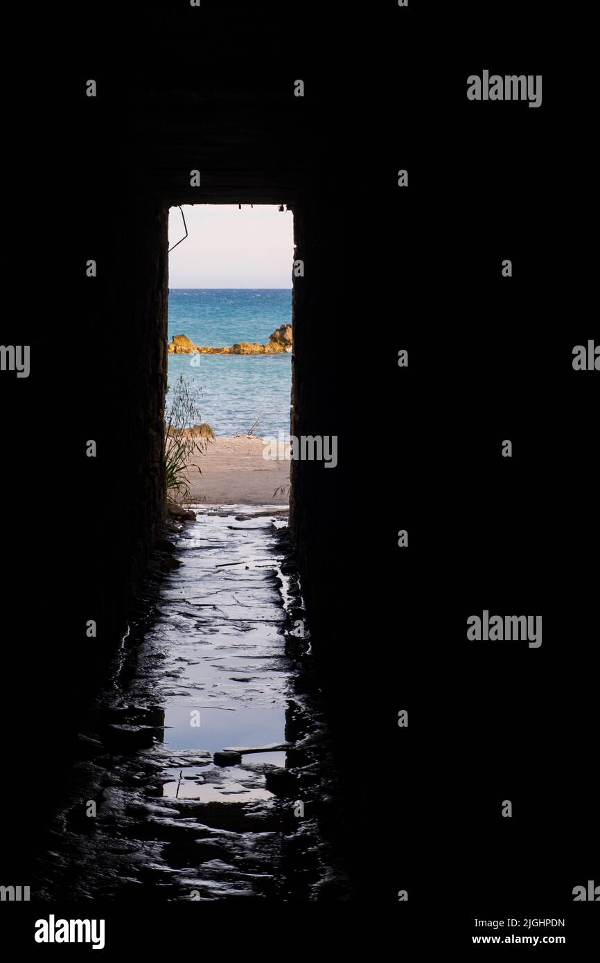 Vista pomeridiana attraverso l'apertura di un sottopassaggio delle rocce e della spiaggia intorno a Petra tou Romiou, a Paphos, Cipro. È considerato come Afrodite' Foto Stock