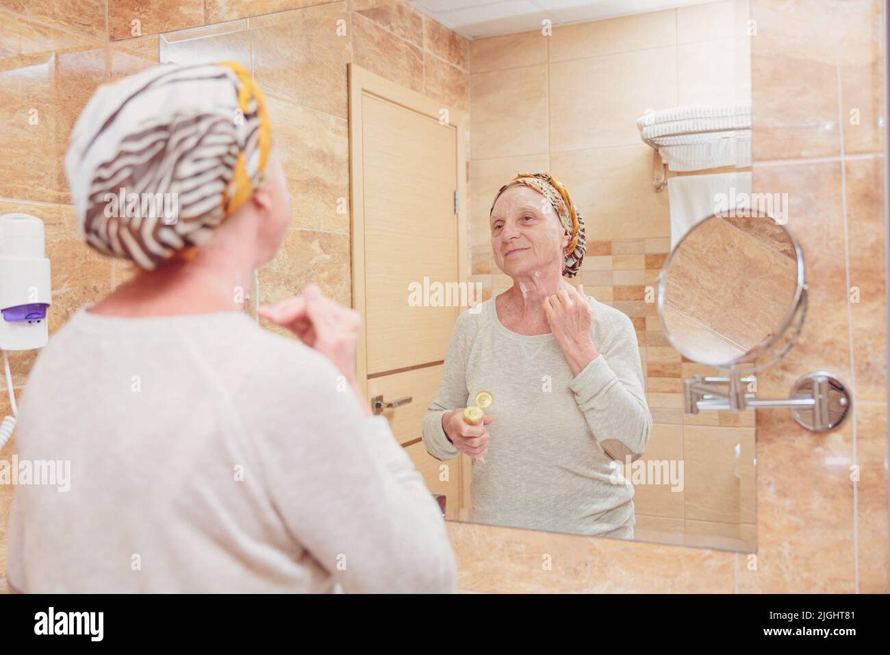 Donna anziana che si prende cura del suo viso Foto Stock