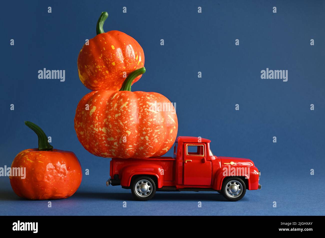 Camion retrò con zucche e foglie su sfondo blu. Concetto di giorno del Ringraziamento, Halloween e cartoline autunnali. Foto Stock