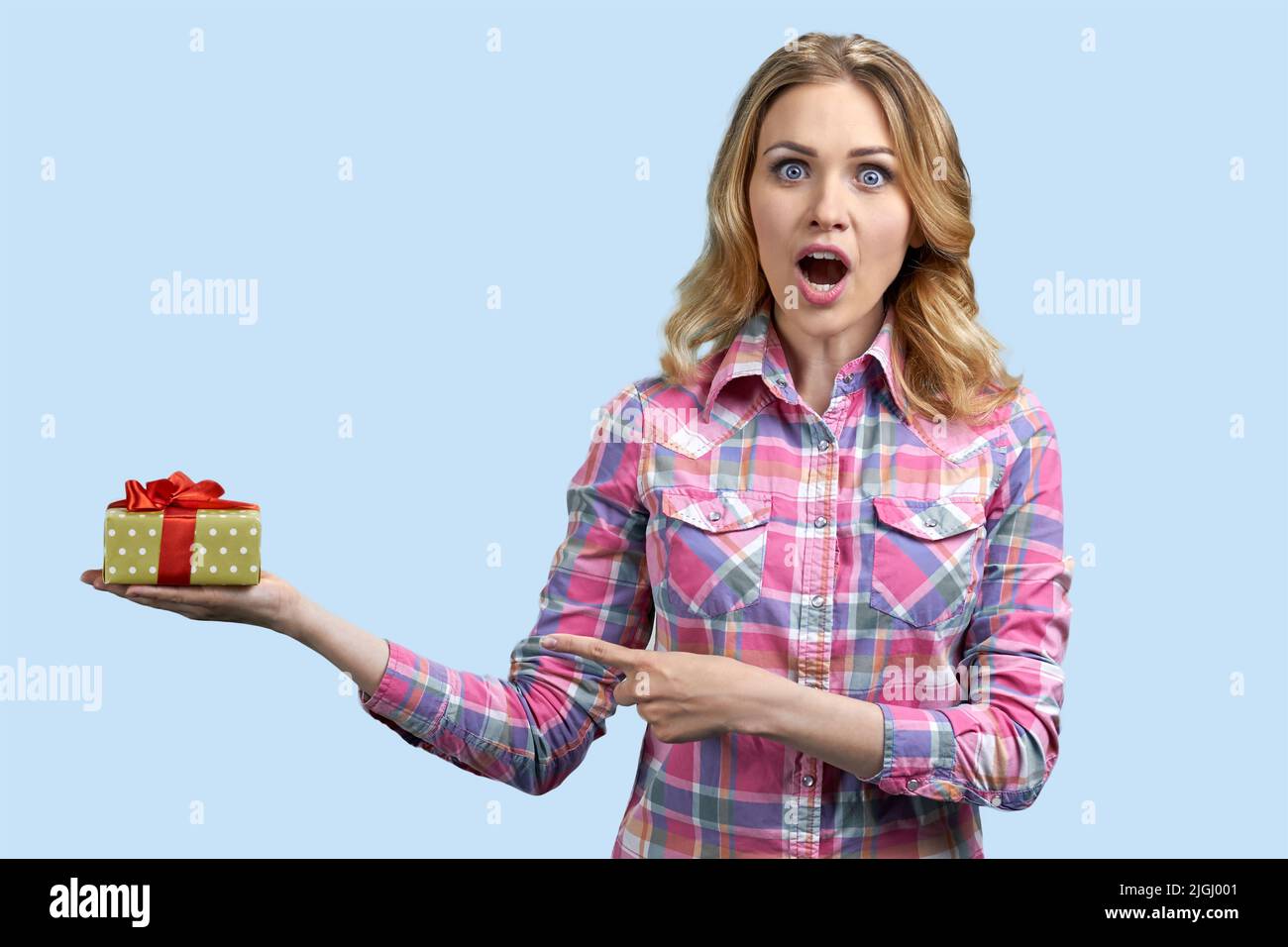 Giovane donna caucasica scioccata che gioisce del suo compleanno presente. Sorpresa donna che tiene la scatola regalo su sfondo colore. Foto Stock