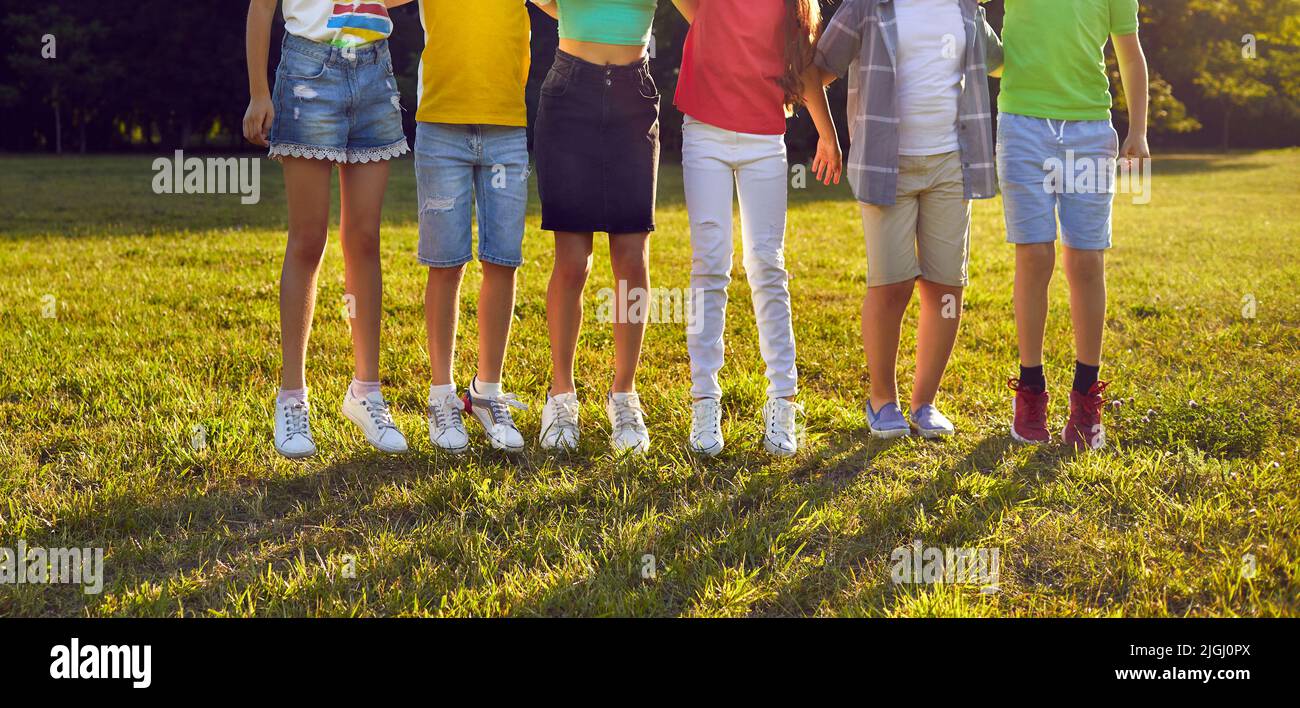 Gruppo di bambini che si divertono nel parco e saltano insieme sull'erba verde Foto Stock