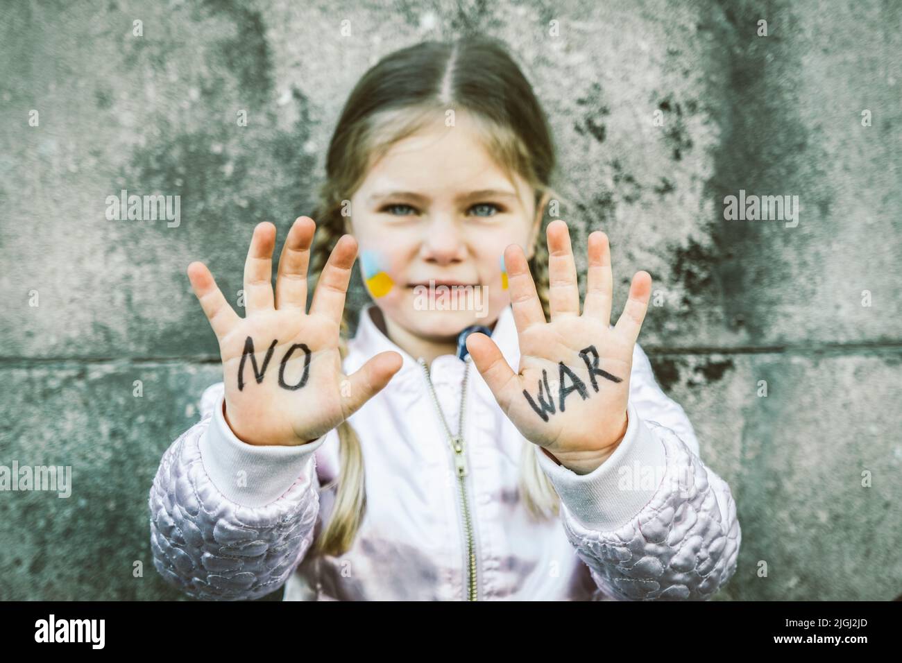 Bella e spaventata iscrizione bambino NON GUERRA sulle sue mani. L'invasione russa dell'Ucraina, bambini contro la guerra Foto Stock