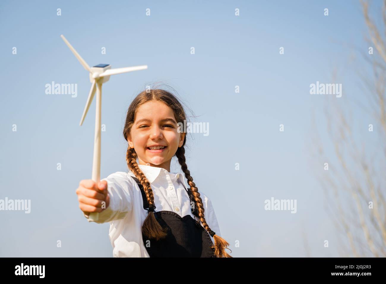 Il bambino gioca e guarda interessato a un giocattolo a turbina eolica - concetto di generazione futura e Enewable Energy Foto Stock