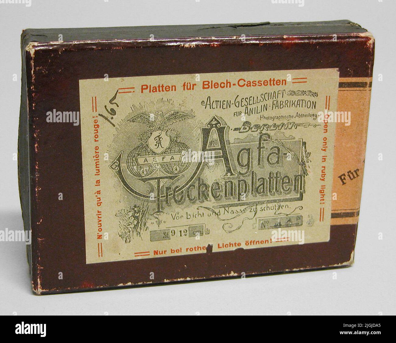 Chiedi ad Ash per canzoni fotografiche, piatti di vetro. Scatola rettangolare marrone rossastro con coperchio. Etichetta gialla bianca con testo nero 'Agfa Trogenplatten'. Testo rosso che include "cassetto piatto für blech". Testo con inchiostro '1,65' (prezzo?). Ha contenuto 12 lastre di vetro 9x12. Nel 1867 viene fondata la produzione Actien-Gesellschaft für Anilin a Rummelsburg. Nel 1964 il belga Gevaert fu fuso. Foto Stock
