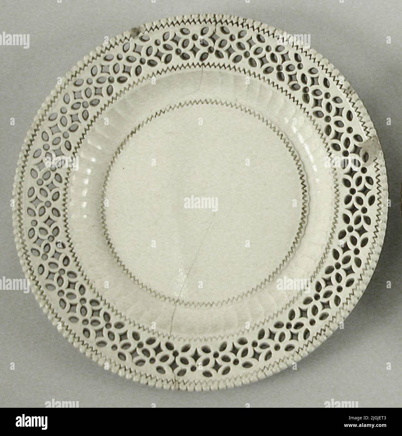 Assiett Asset, di prodotti di selce con glassa crema. Dio -fed buco e trafitto in ornamenti di fiori. Al bordo una barra della perla. Danneggiato, bordo supportato e crepe.EJ firmato. Inghilterra Leeds? Potrebbe essere pubblicato leed Work. Nel 1901 Foto Stock