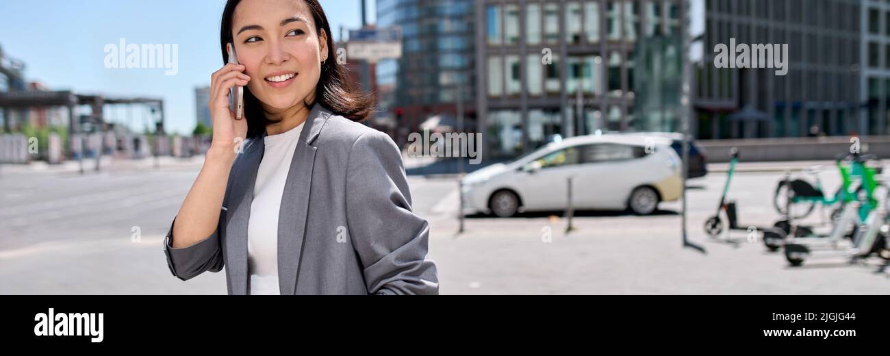 Giovane donna felice asiatico d'affari indossa vestito parlare al telefono sulla strada della città. Foto Stock