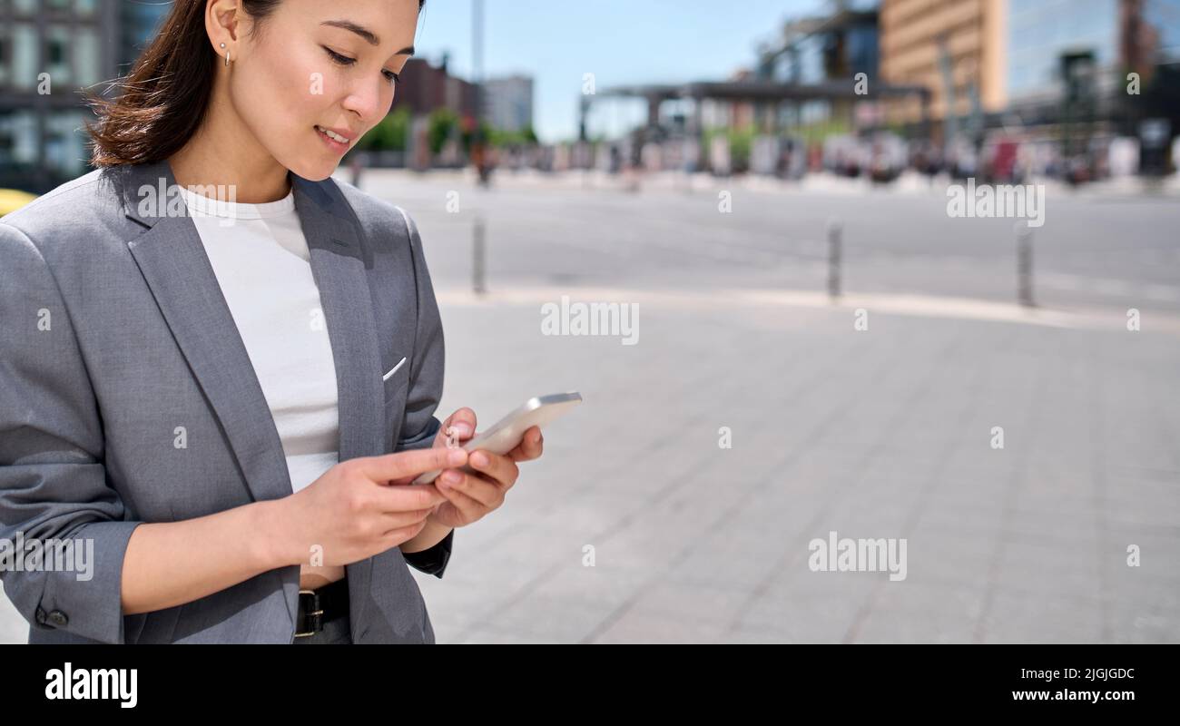 Giovane donna d'affari asiatica che usa lo smartphone in città all'aperto. Foto Stock