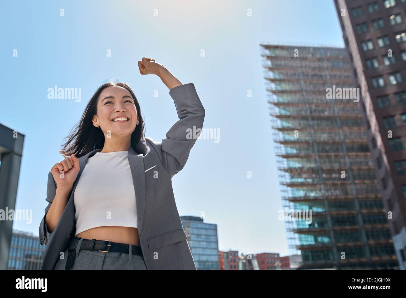 Giovane entusiasta fiduciosa donna asiatica d'affari che sente vincitore nella grande città. Foto Stock