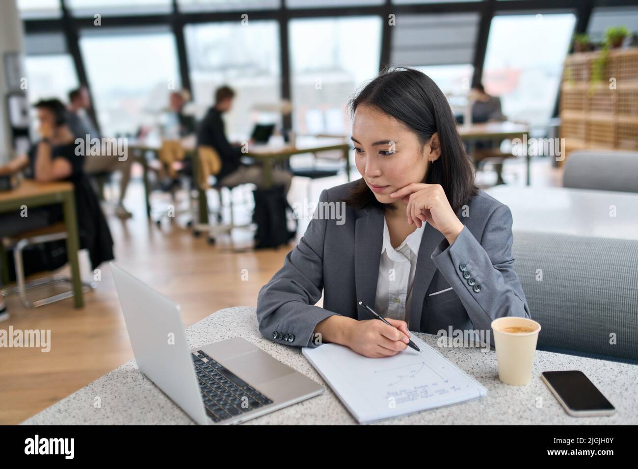 Giovane donna asiatica d'affari che usa il laptop che lavora in un grande ufficio moderno. Foto Stock