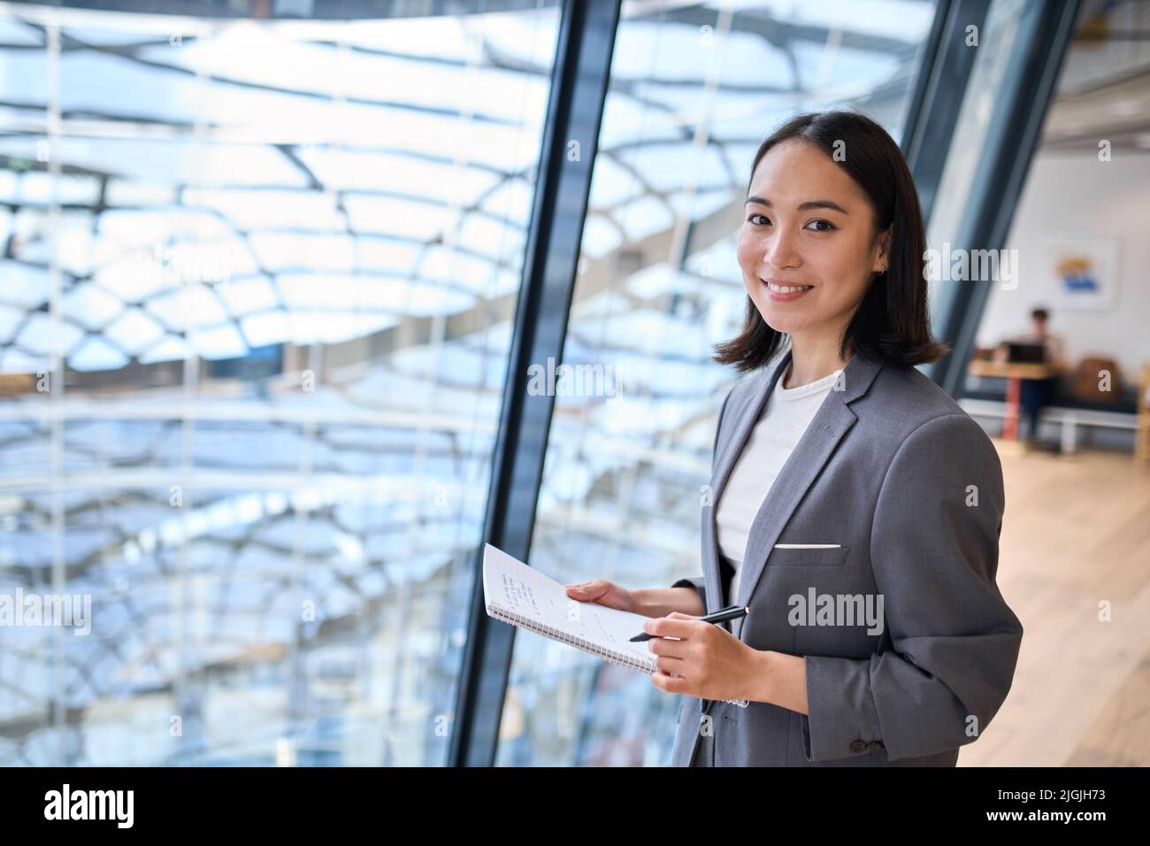Sorridente giovane donna asiatica d'affari manager in piedi in ufficio. Foto Stock