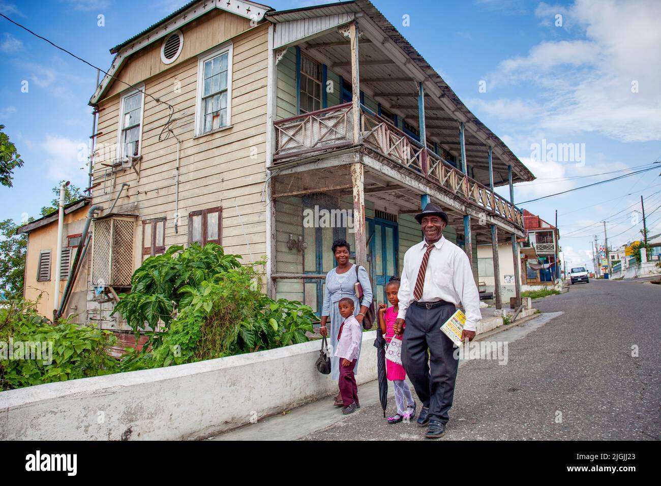 Giamaica, St. Ann's Bay, case in legno dove si mostra l'architettura tradizionale. La famiglia in cammino verso la messa di domenica. Foto Stock