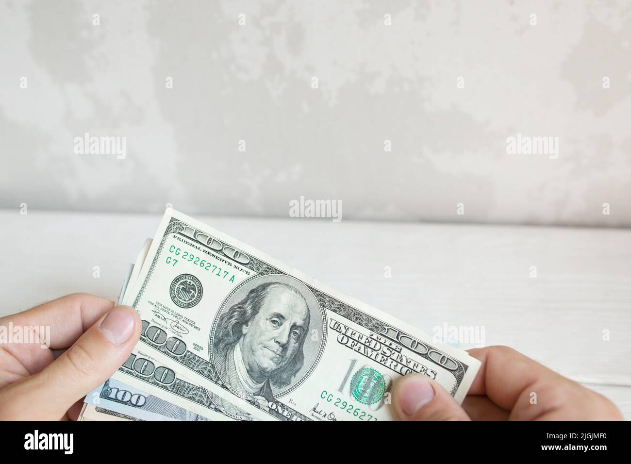 Mano maschile che contiene cento banconote da dollaro Foto Stock