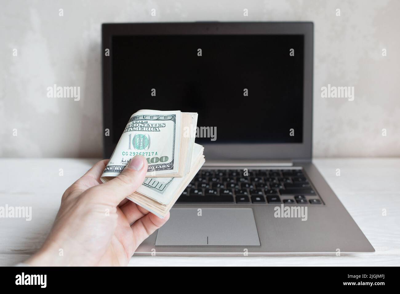 Un mazzo di centinaia di dollari di bollette e laptop Foto Stock