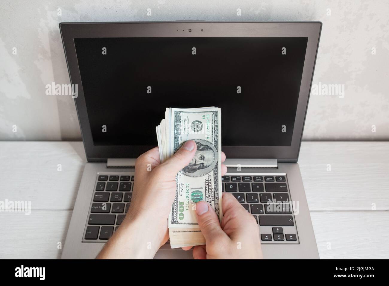 La mano maschile ha messo il dollaro bankmotes nello schermo del portatile Foto Stock
