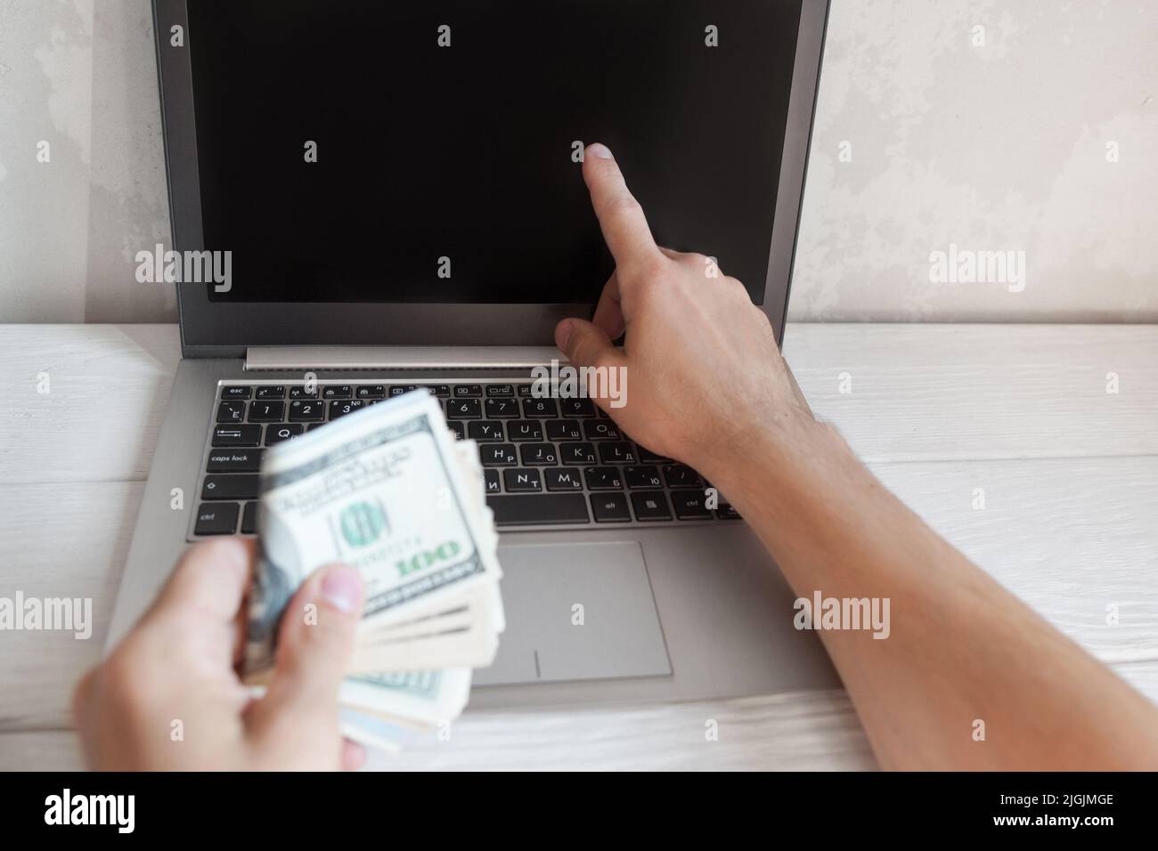 L'uomo mostra qualcosa sullo schermo del portatile con soldi Foto Stock