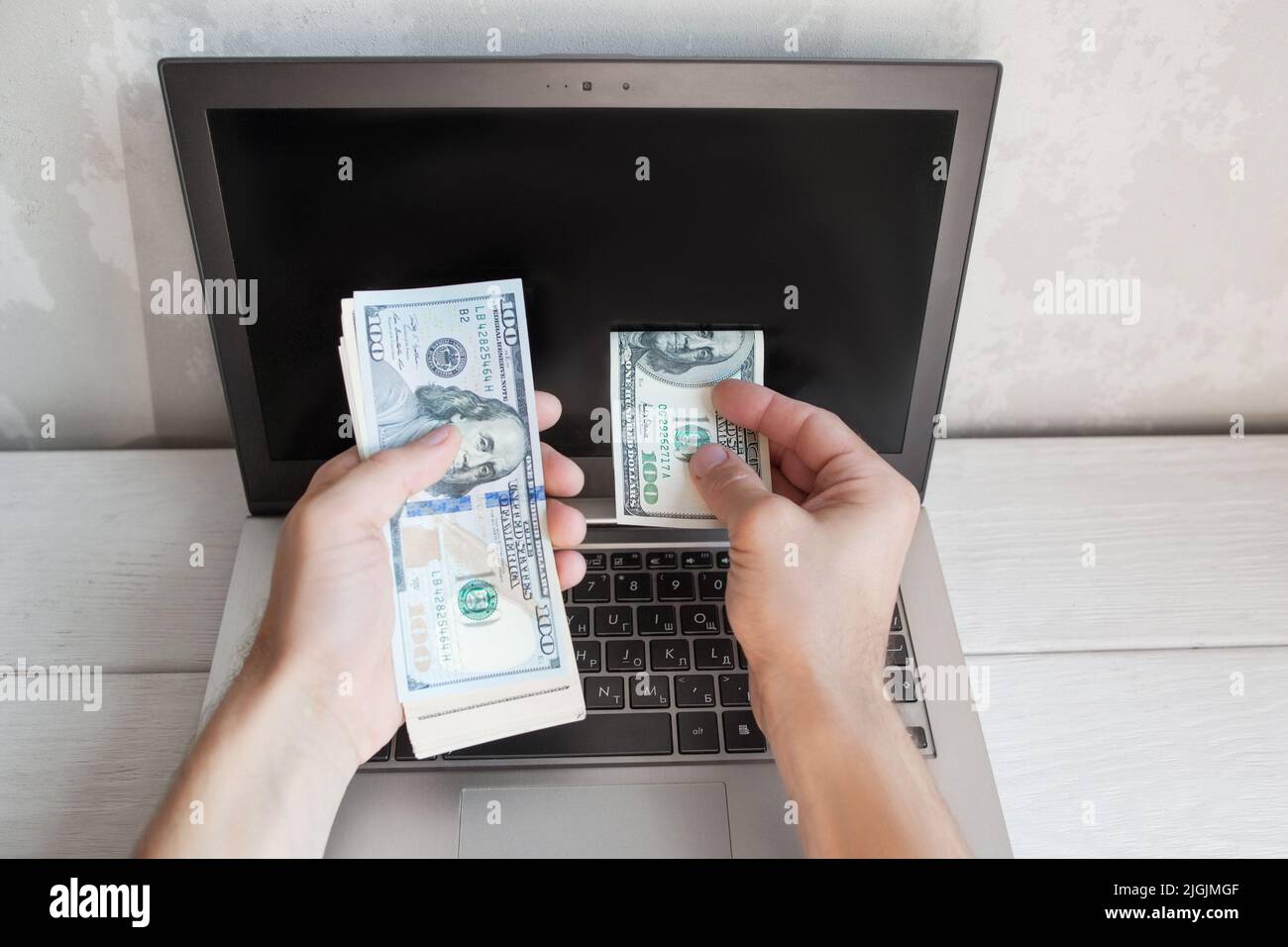 L'uomo ha messo la fattura del dollaro dal lotto allo schermo del laptop Foto Stock