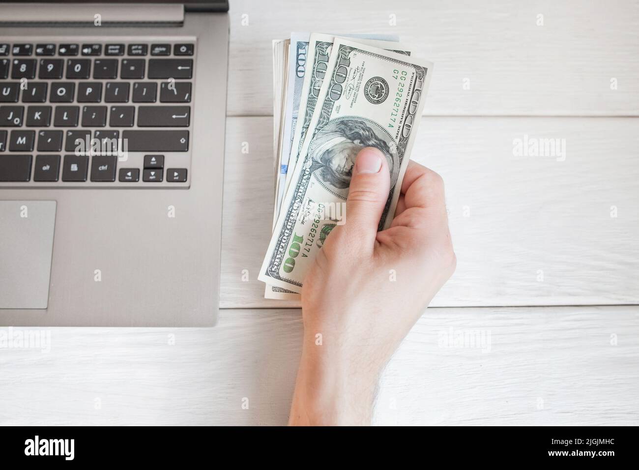 Uomo che tiene dollari vicino al portatile, spazio libero Foto Stock