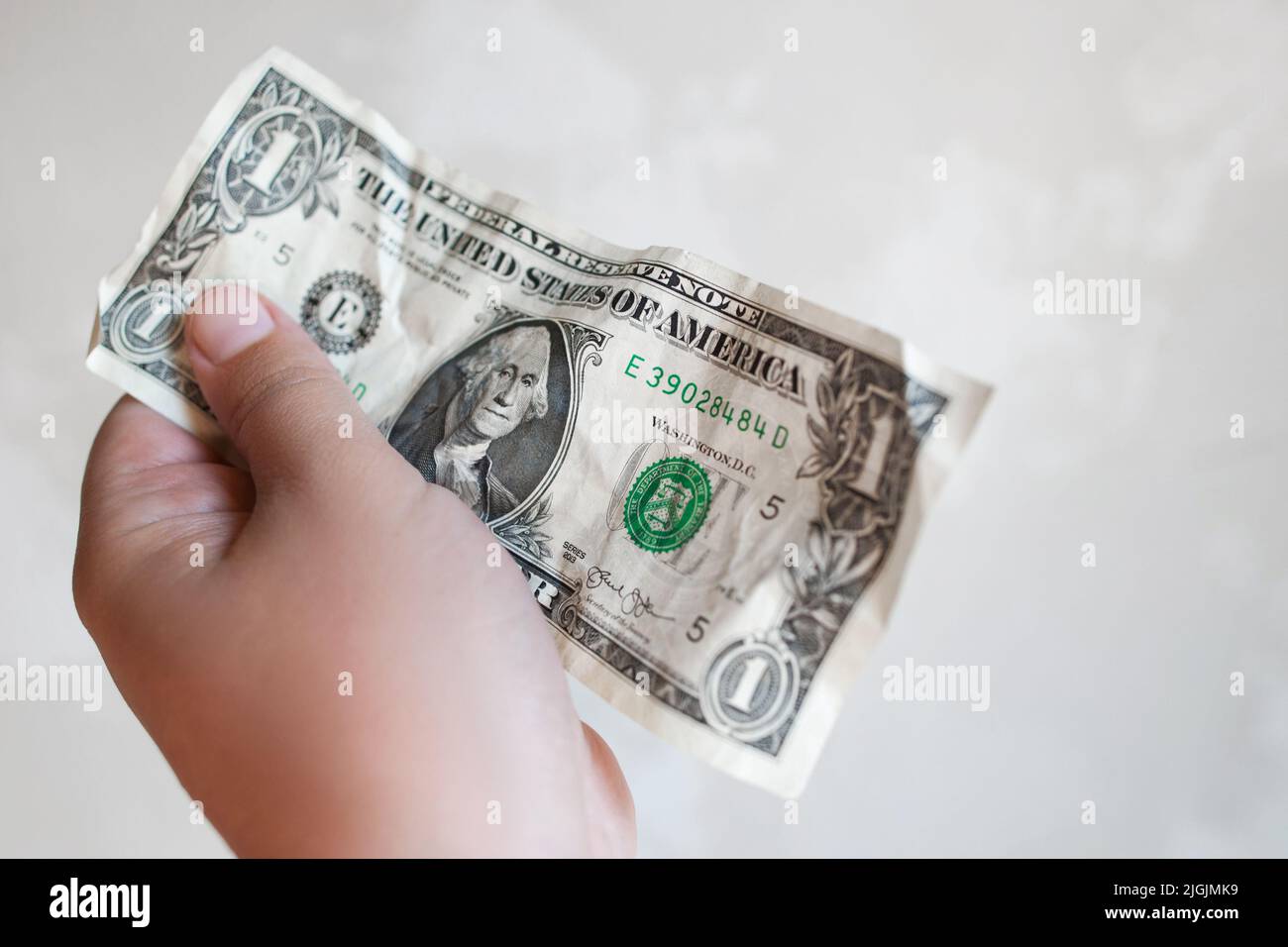 La mano maschile tiene un dollaro di fattura nel dare il gesto Foto Stock