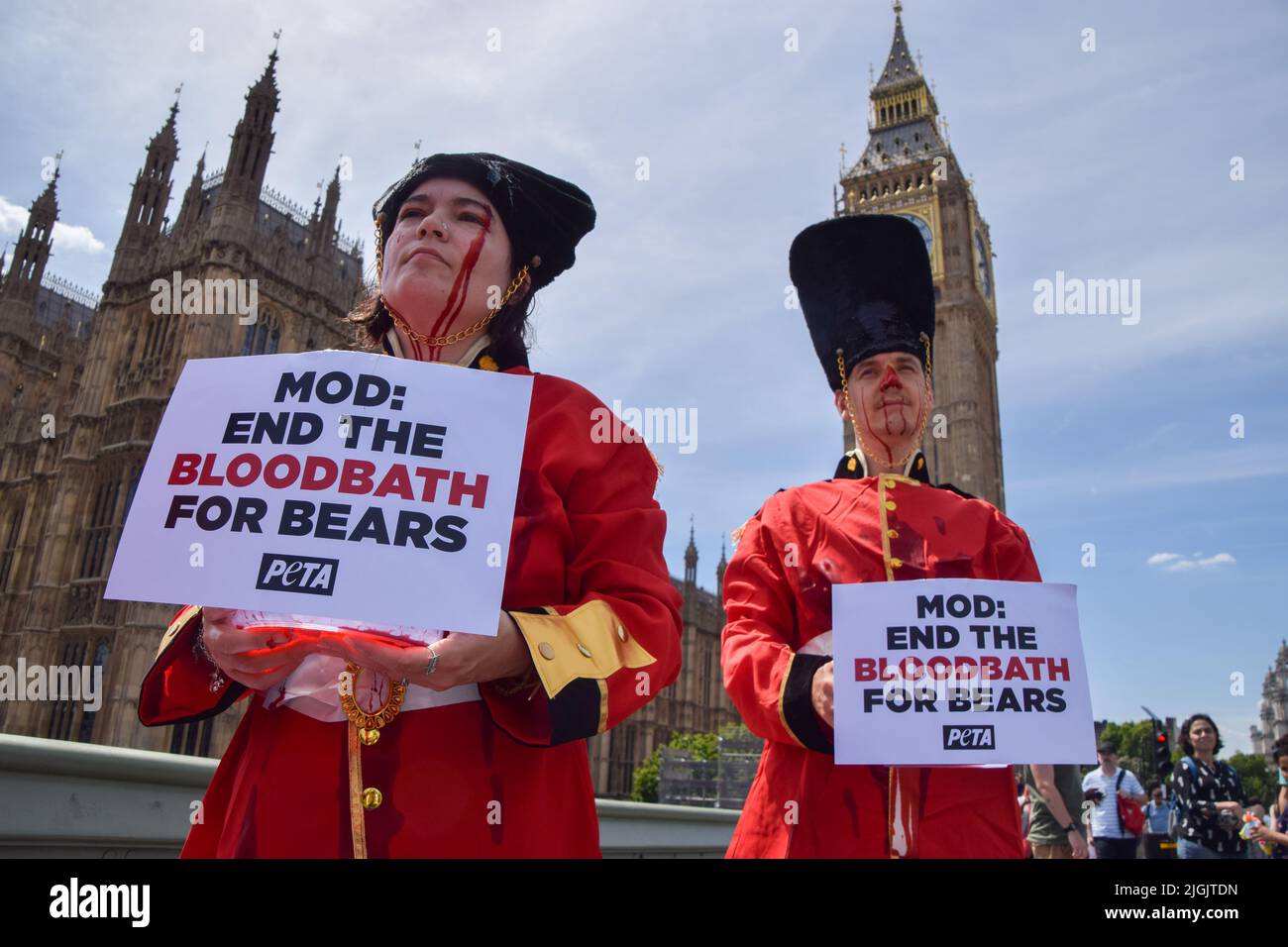 Londra, Regno Unito. 11th luglio 2022. Gli attivisti DI PETA che indossavano i costumi della Queen's Guards, coperti di sangue falso e in piedi su Union Jacks macchiati di sangue, hanno organizzato una protesta contro l'uso di pelli di orso nei cappucci della Queen's Guards sul Ponte di Westminster fuori dal Parlamento. Attualmente, il Ministero della Difesa utilizza la vera pelliccia di orso per fare le calotte, e ci vuole un orso per fare solo una testa. PETA ha contribuito a sviluppare un'alternativa adatta alla pelliccia sintetica, che il MOD ha finora rifiutato di utilizzare. Credit: Vuk Valcic/Alamy Live News Foto Stock