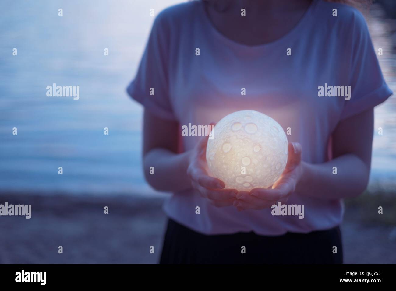 Astrologia concetto Donna su una spiaggia di notte con la luna in mano. Foto Stock