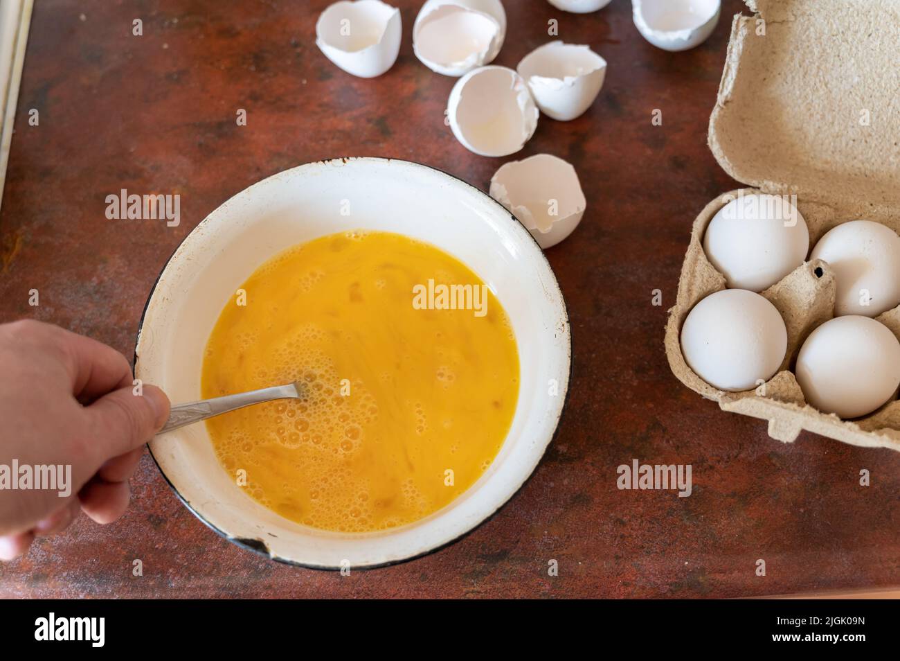 Cottura di waffle crosts farciti con carne tritata. Sequenza passo per passo. L'uomo prepara la pastella per friggere brizoles. Mescola le uova di pollo crude in un recipiente. Casa Foto Stock