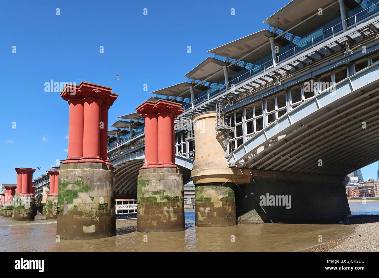 I moli del vecchio ponte vittoriano Blackfriars si trovano nel Tamigi, accanto all'attuale ponte ferroviario che supporta la nuova stazione Blackfriars. Foto Stock