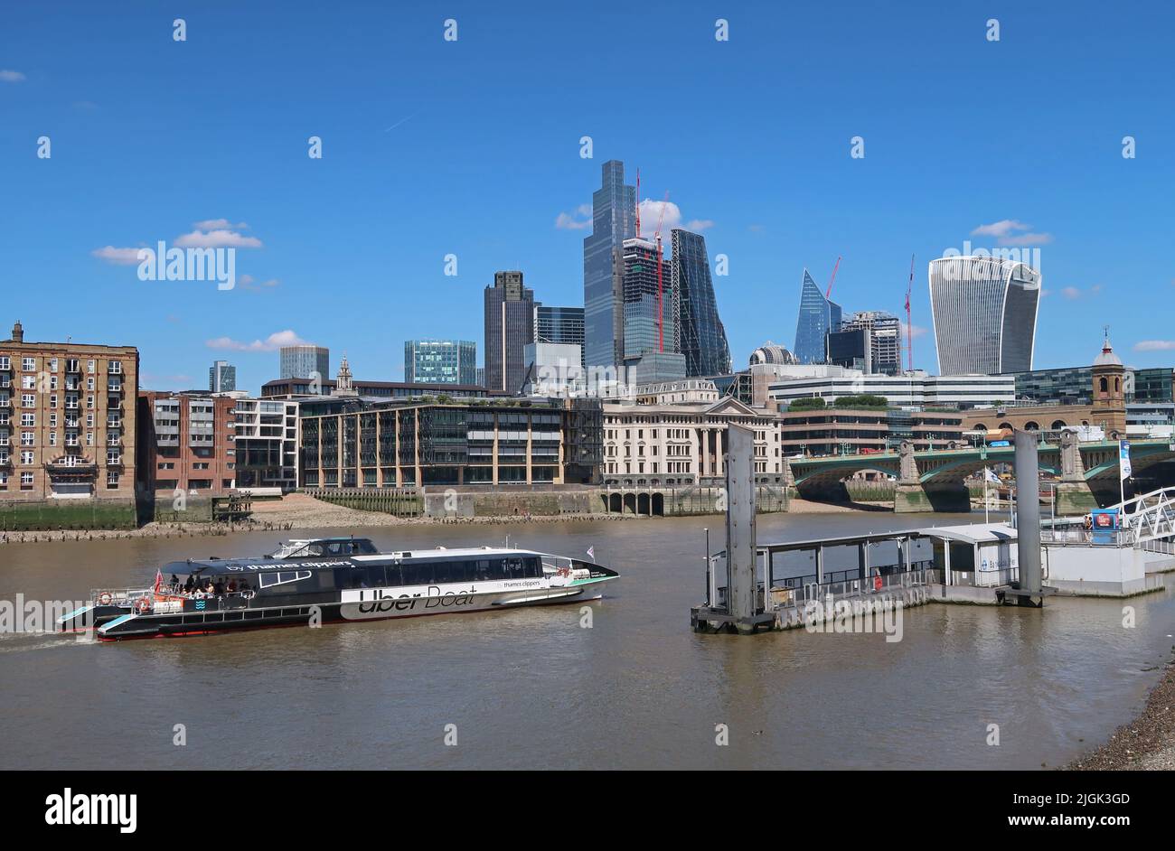 Una barca sul fiume Uber arriva al molo di Bankside sulla riva sud del Tamigi. Città di Londra skyline oltre. Foto Stock