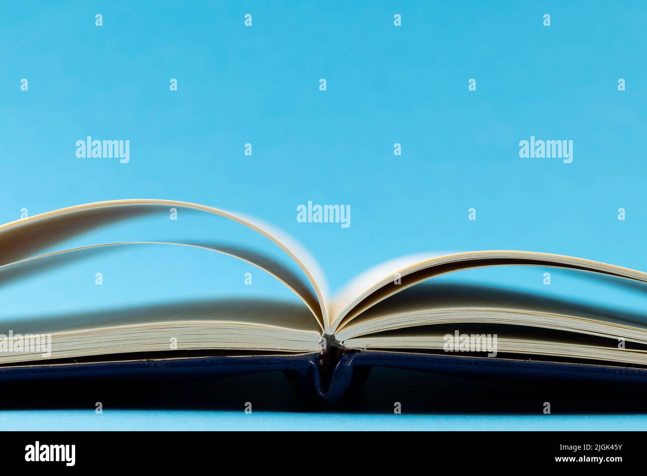 Immagine di un libro aperto con copertina blu navy su sfondo blu Foto Stock