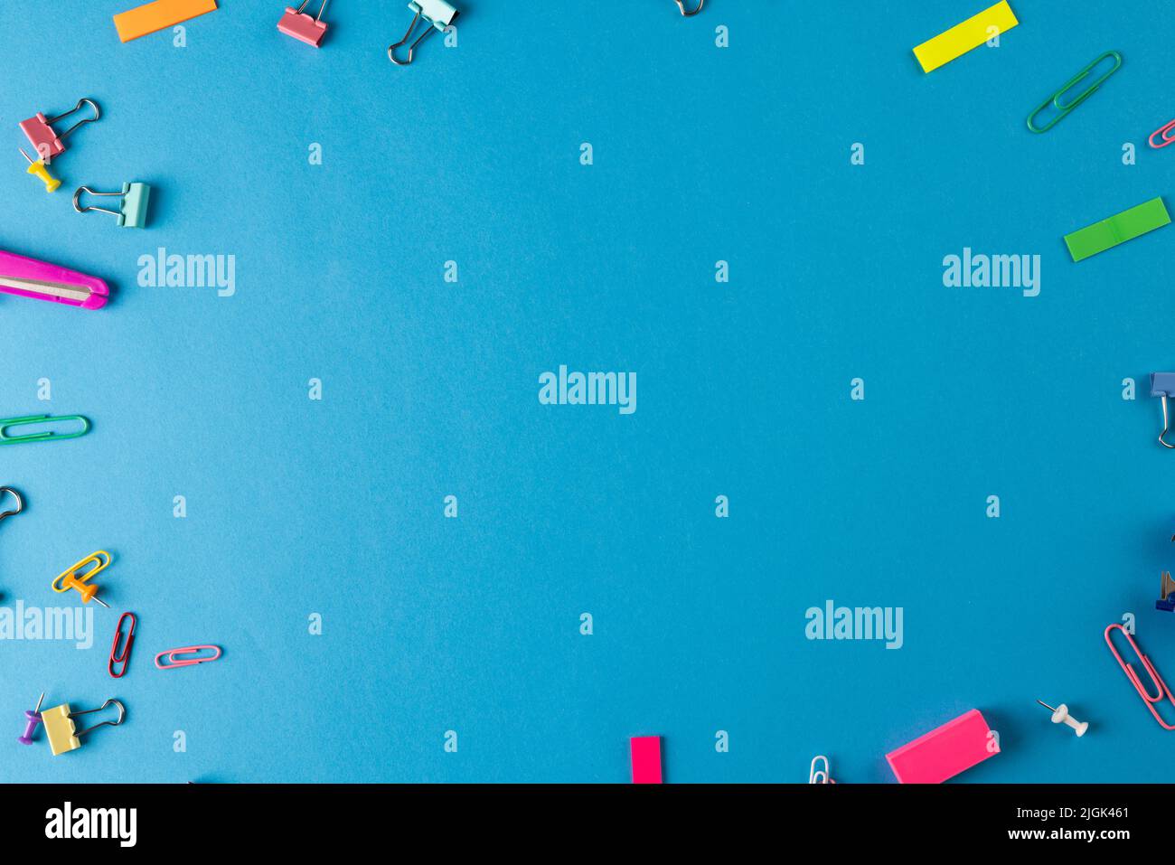 Immagine di vari materiali di consumo per ufficio, , graffette, spilli e foglio di carta bianco su sfondo blu Foto Stock