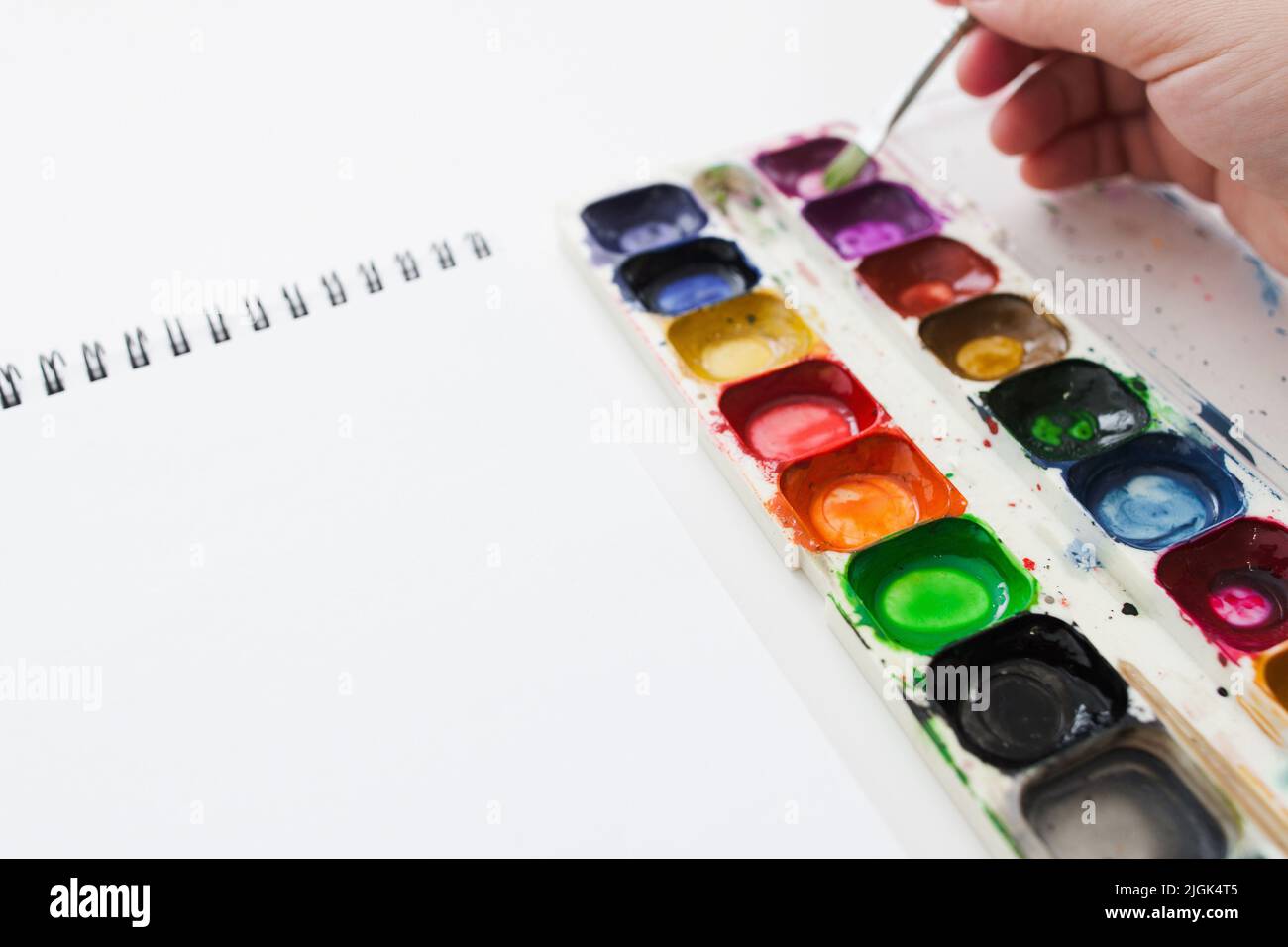 Mano d'artista con tintura acquerello e taccuino Foto Stock