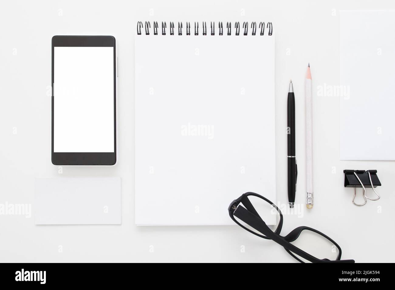 Blocco note vuoto con smartphone e occhiali a disposizione piatta Foto Stock